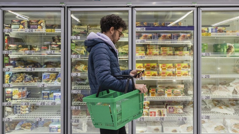 A person shopping in a grocery store freezer aisle.
