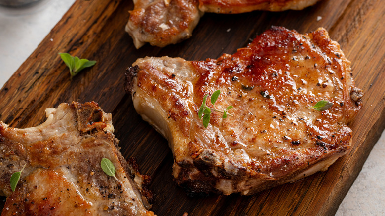 A bone-in pork chop pan-fried golden brown on a cutting board
