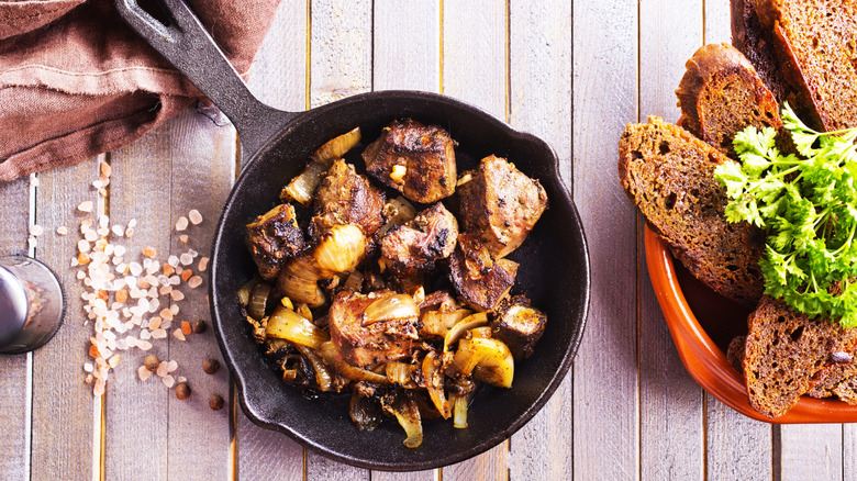 Chicken liver in a cast iron pan with rye bread on the side