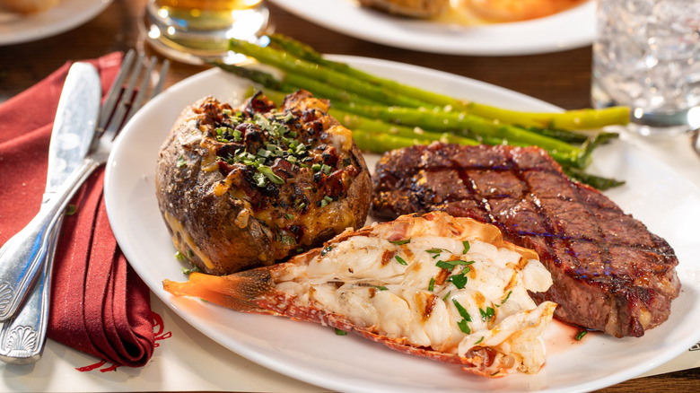 Plate with steak, lobster tail, baked potato and asparagus
