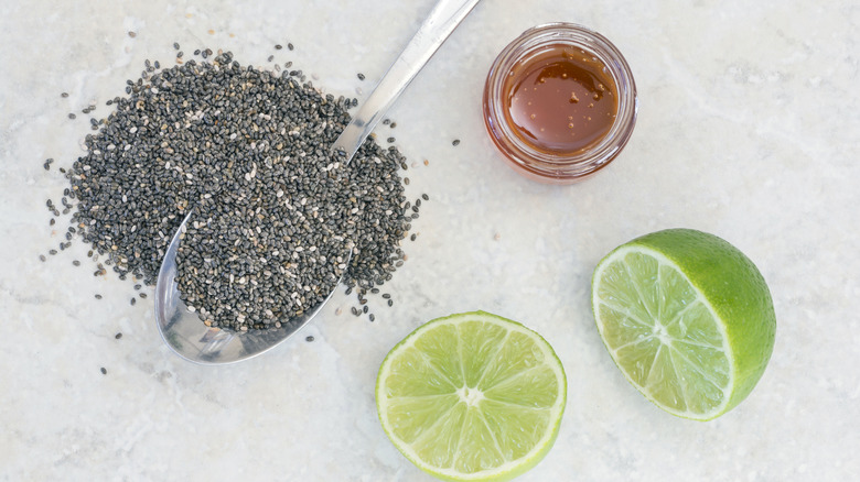 Ingredients for iskiate on a marble countertop, including lime, chia seeds, and agave.