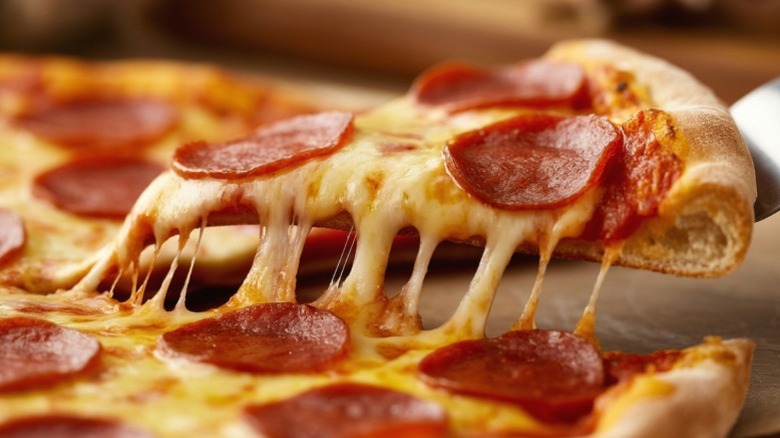 A slice of pepperoni pizza being pulled from a pie.