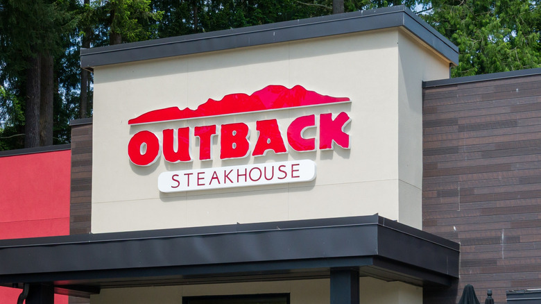 Outback Steakhouse restaurant exterior signage in front of green trees