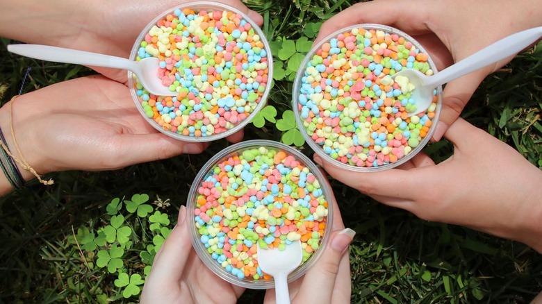 Top down view of three people holding Dippin' Dots cups with spoons