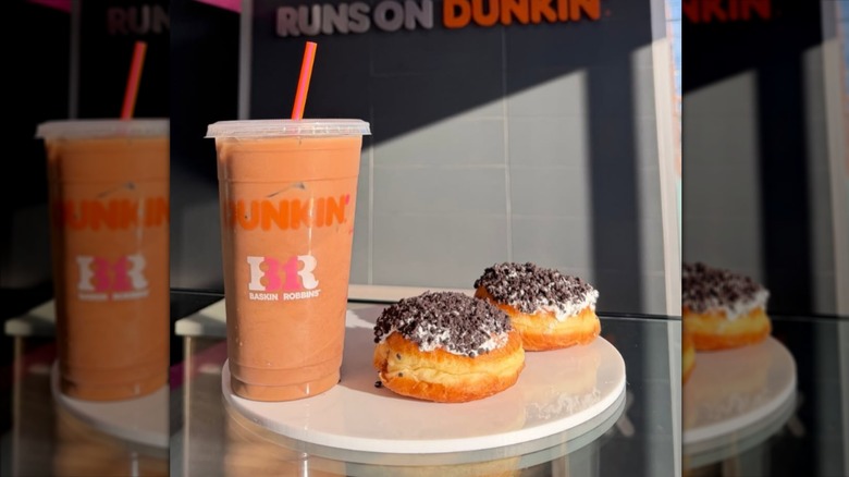 Two Ice Cream Cake Donuts sit on a table next to a Dunkin' drink