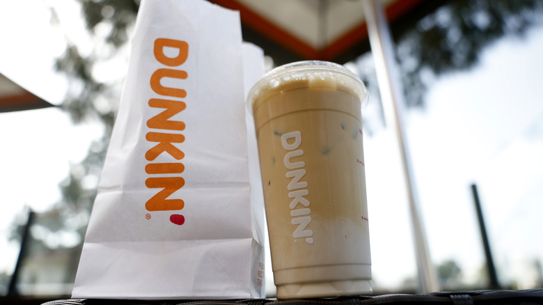 A paper Dunkin' bag with a drink on a table