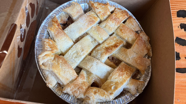 An apple pie with a lattice pastry crust in a disposable pie tin sits inside a takeout box from Black Bear Diner