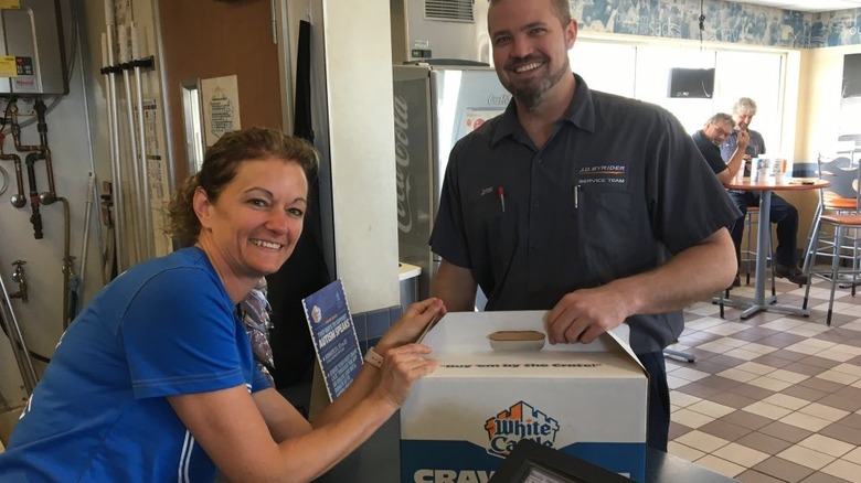A photo of White Castle CEO Lisa Ingram in a store with a big box of White Castle sandwiches.