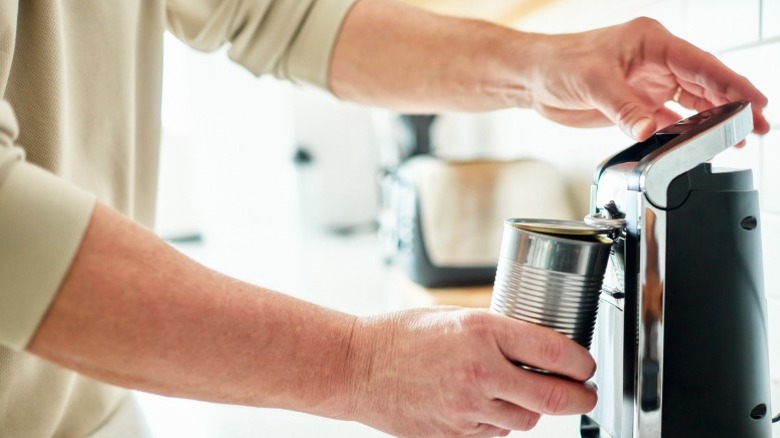 Someone using an electric can opener to open a label-less can