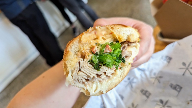 hand holding pork and green's sandwich