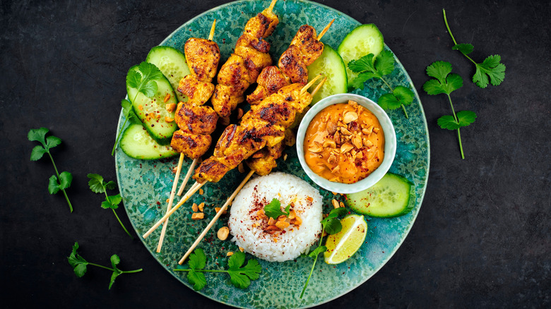rilled chicken satay skewers with peanut dipping spicy sauce, steamed rice, and fresh cucumber