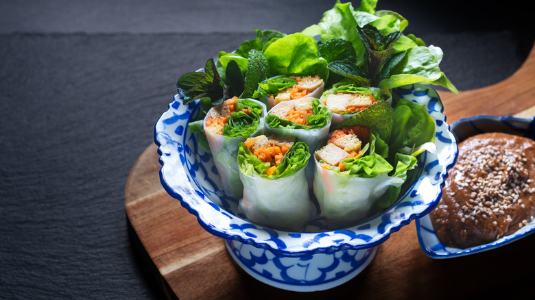 A bowl of vegan tofu summer rolls with peanut dipping sauce