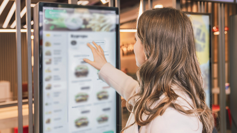 A woman ordering from an electronic menu screen