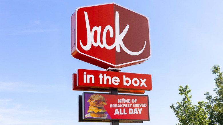 A sign for Jack in the Box against a blue sky