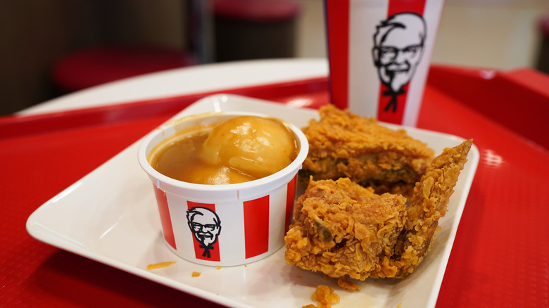 Fried chicken, mashed potatoes, and a drink in KFC packaging in a restaurant