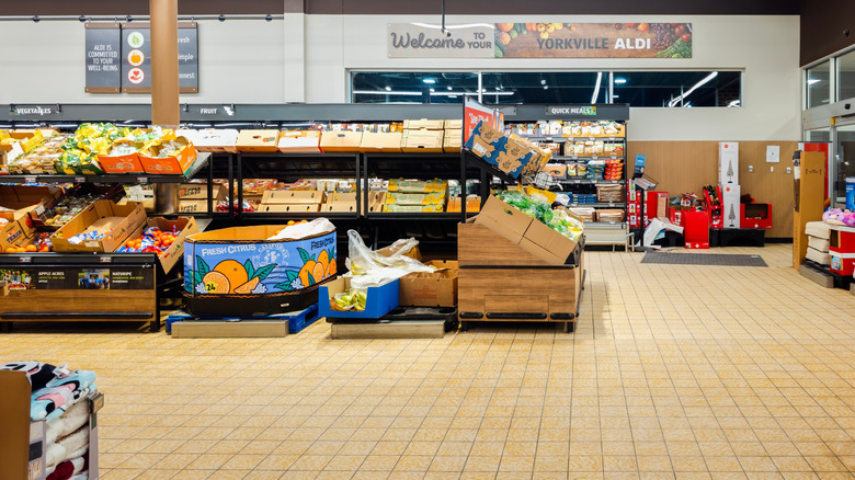 produce section of Aldi store featuring shelves of produce in cardboard shipping boxes