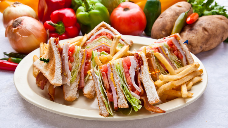 A club sandwich with fries served on a white plate.