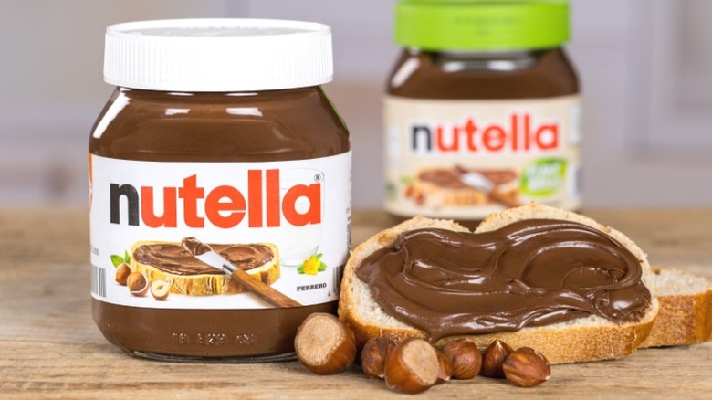 A jar of Nutella next to a slice of bread smeared with Nutella