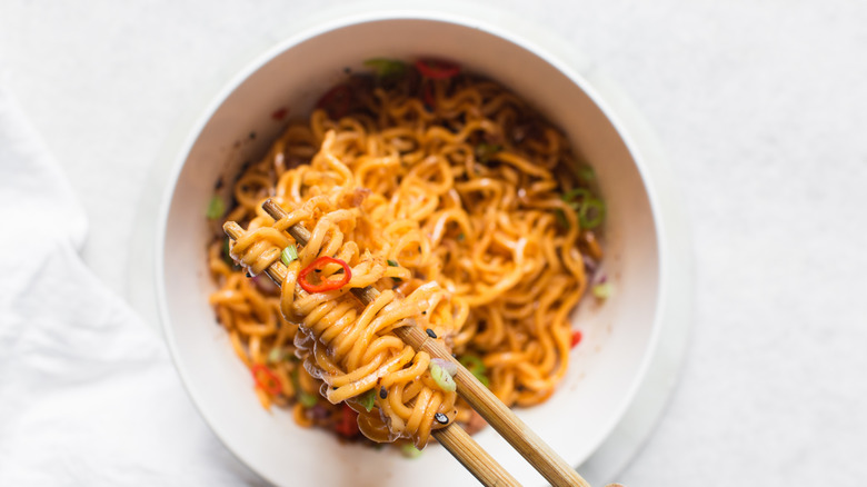 aerial view of chopsticks lifting ramen from a bowl of ramen