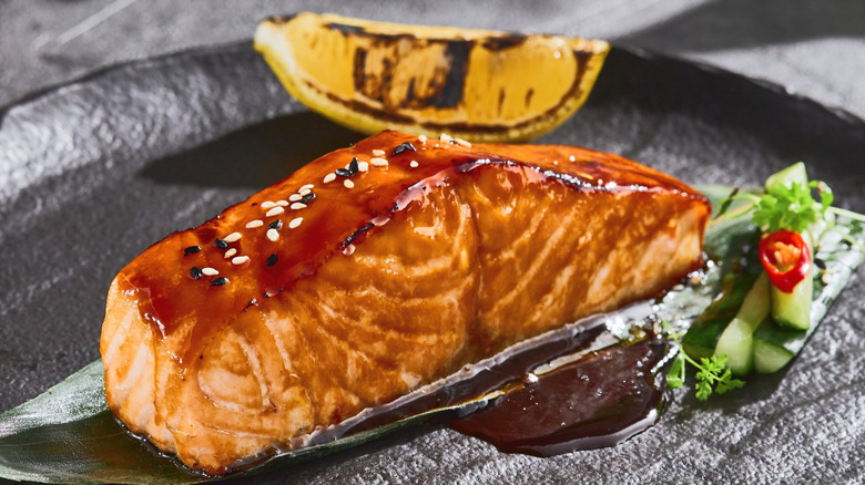 miso-glazed salmon with sesame seeds and a charred lemon wedge
