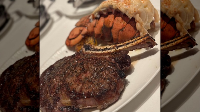 A bone-in ribeye on a white plate next to a lobster tail at Fleming's chain restaurant.