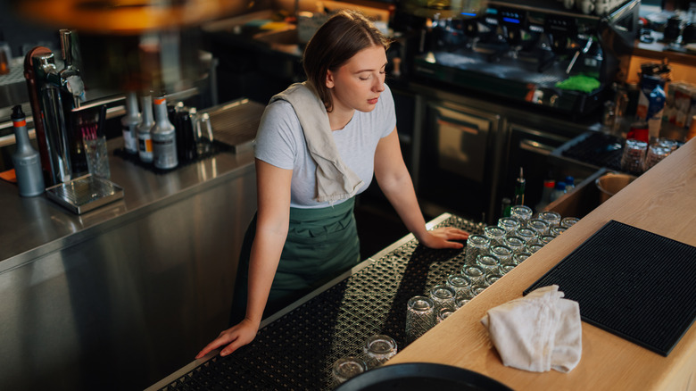 Bartender with their eyes closed behind the bar