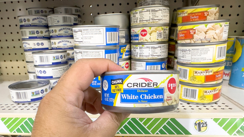 A view of a hand holding a can of Crider canned chicken, at the store.