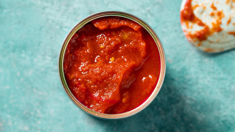 Open can of tomatoes on blue background