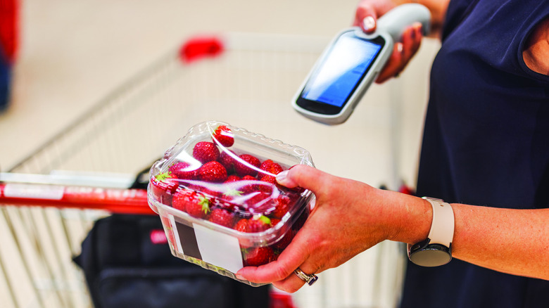 An employee holding a scanner with strawberries