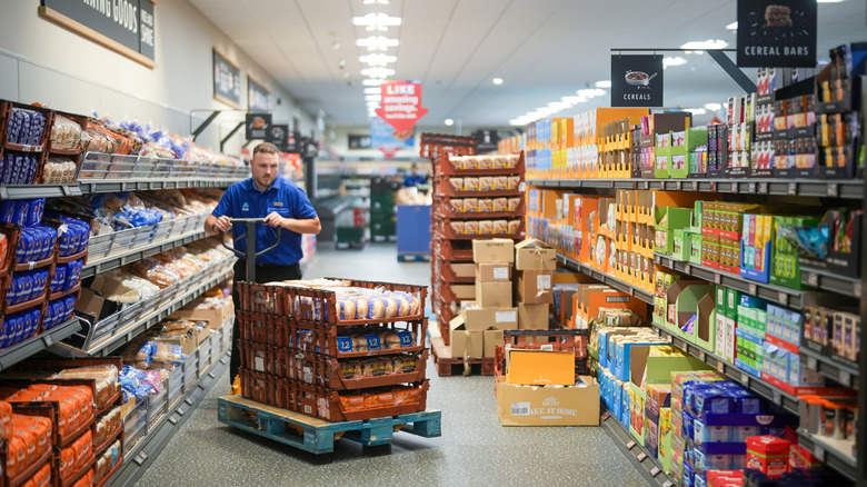 Aldi worker pushing food trolley through store