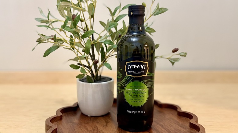 A one-liter bottle of Ottavio Early Harvest extra virgin olive oil beside a mini decorative olive tree