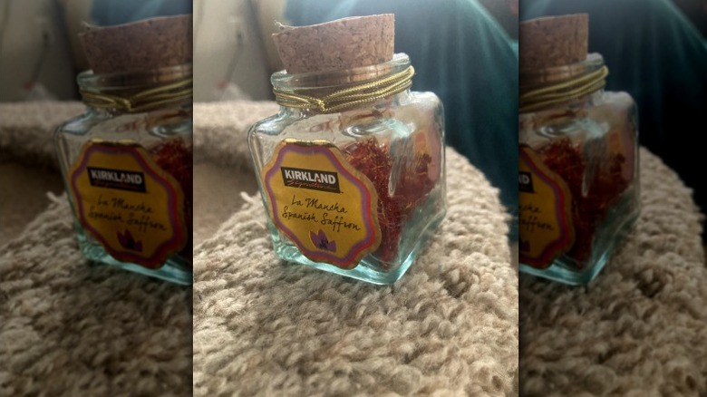 A container of the Kirkland Signature Organic La Mancha Spanish Saffron sitting on a fuzzy surface.
