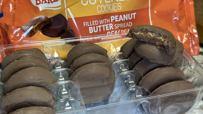 Oven Baked Fudge Covered Peanut Butter cookies in the packaging tray, one on top with a bite taken out