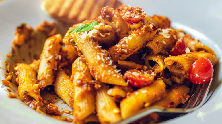 Creamy penne pasta in a tomato-based sauce, topped with fresh basil and grated cheese, served with grilled garlic bread.