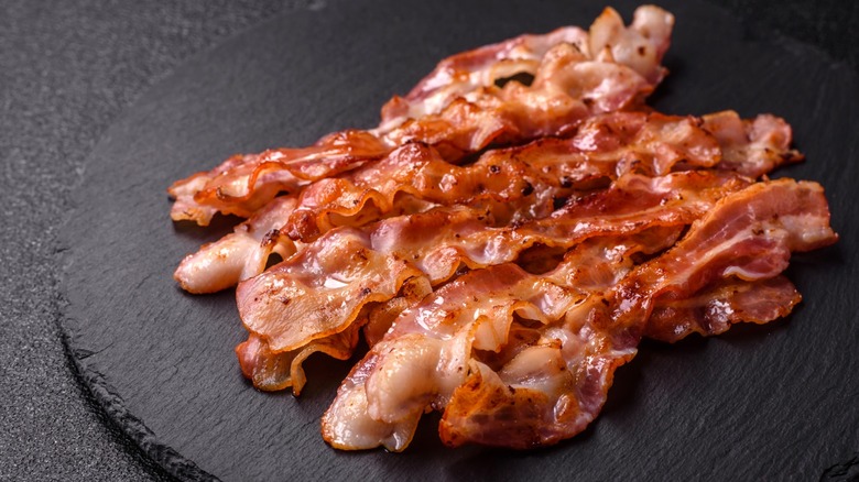 Cooked bacon strips on black surface