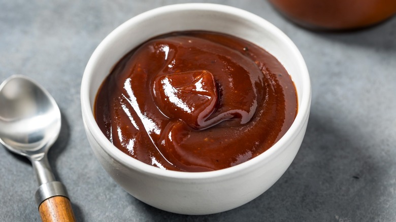 BBQ sauce in white bowl next to spoon