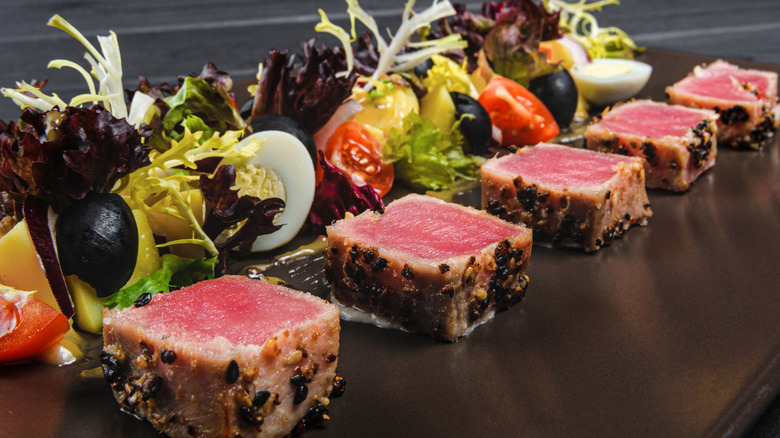 Sesame seared ahi tuna on black tray with garnishes