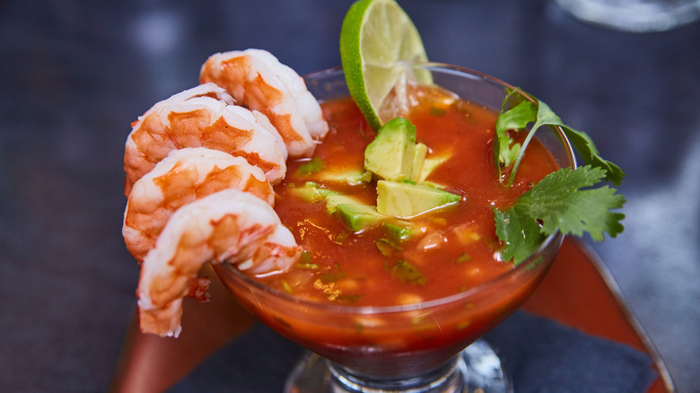Four jumbo shrimp on rim of glass with cocktail sauce