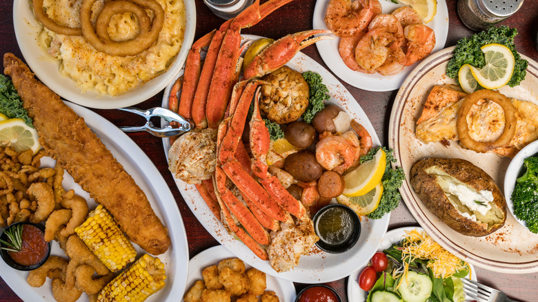Various plates of steamed and fried seafood and vegetables on table