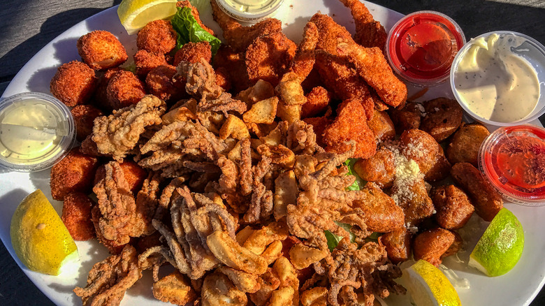 Fried seafood platter on white plate with lemons and dipping sauces