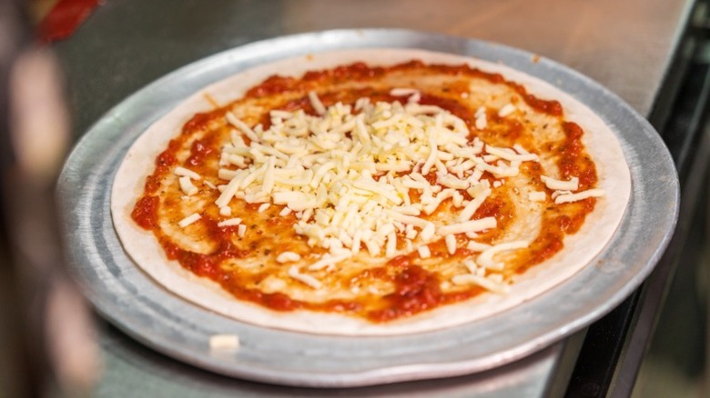 uncooked pizza with sauce and cheese on a baking steel