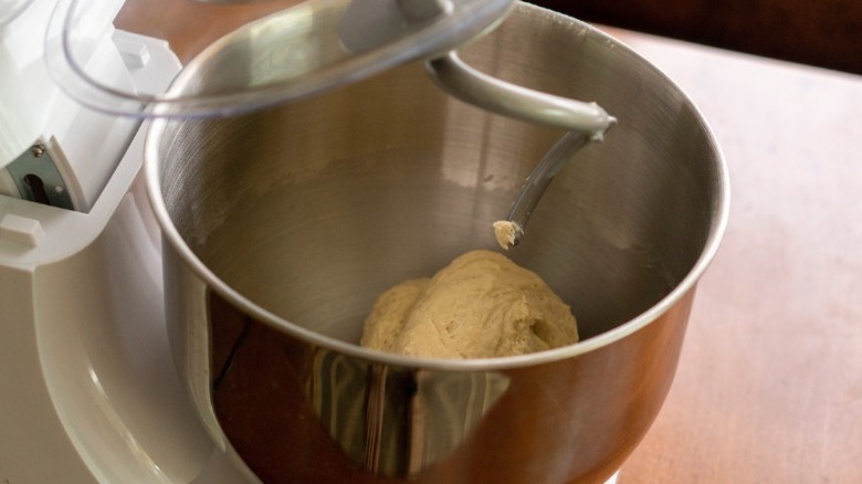 stand mixer equipped with a metal bowl with dough inside and a dough hook