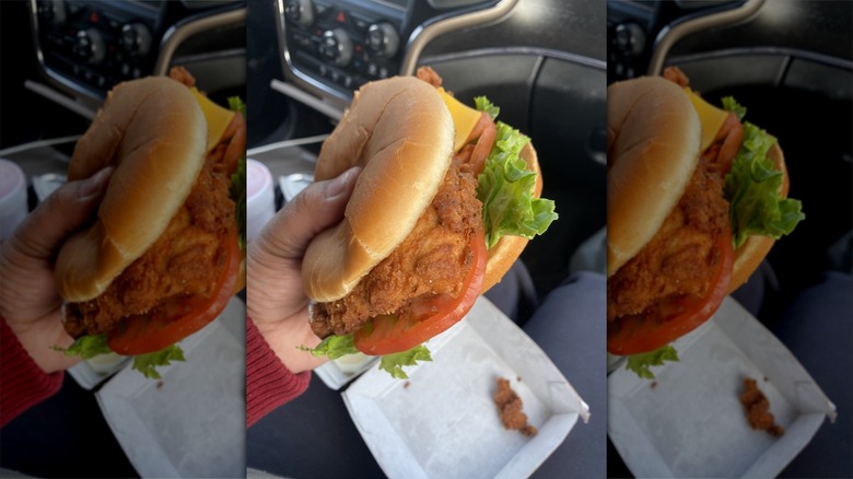 Hand holding Spicy Deluxe Sandwich from Chick-fil-A in car