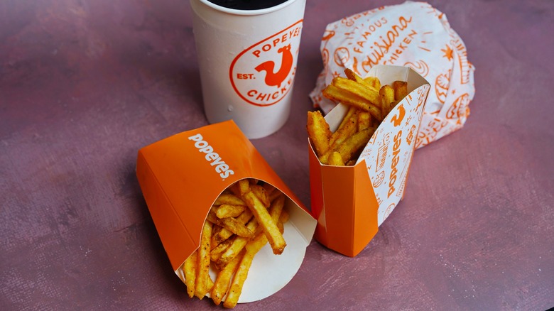 Two portions of fries with Popeyes drink and wrapped sandwich