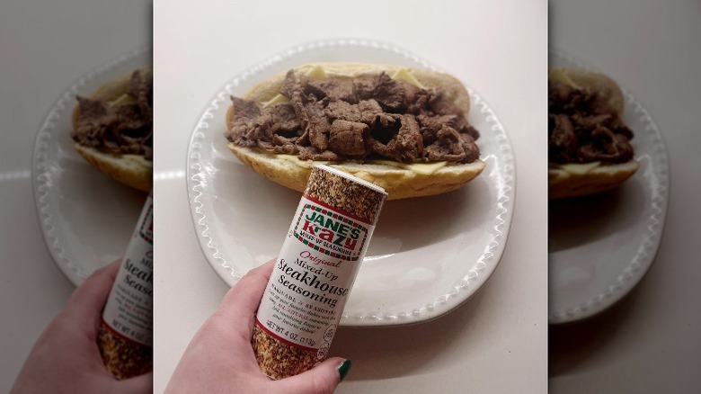 hand holding Jane's Krazy Mixed-Up Steakhouse Seasoning over cheesesteak