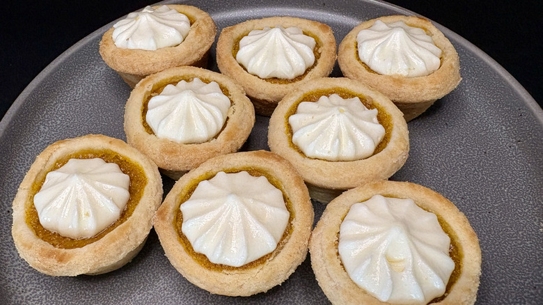 multiple mini pumpkin pies on gray plate, black background