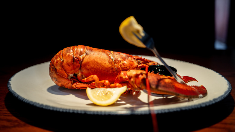 Plate with lobster and lemon slices on wooden table