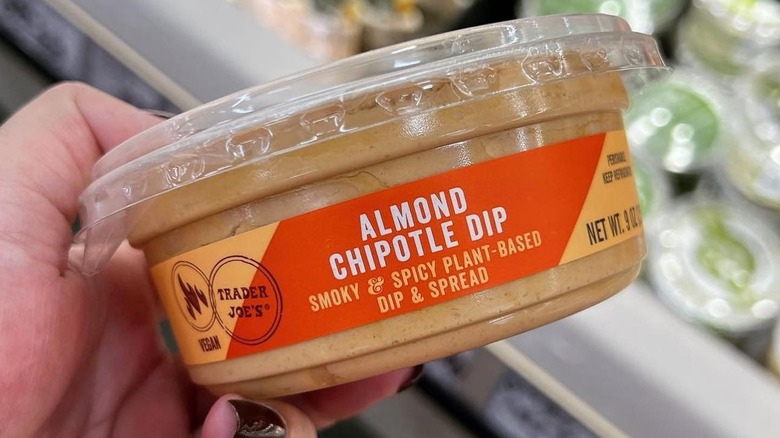 A hand holding a container of Trader Joe's Almond Chipotle Dip.