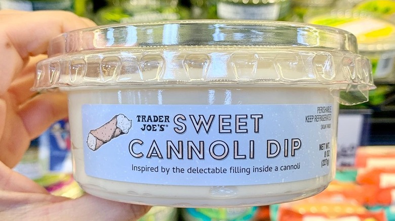 A hand holding a container of Trader Joe's Sweet Cannoli dip.