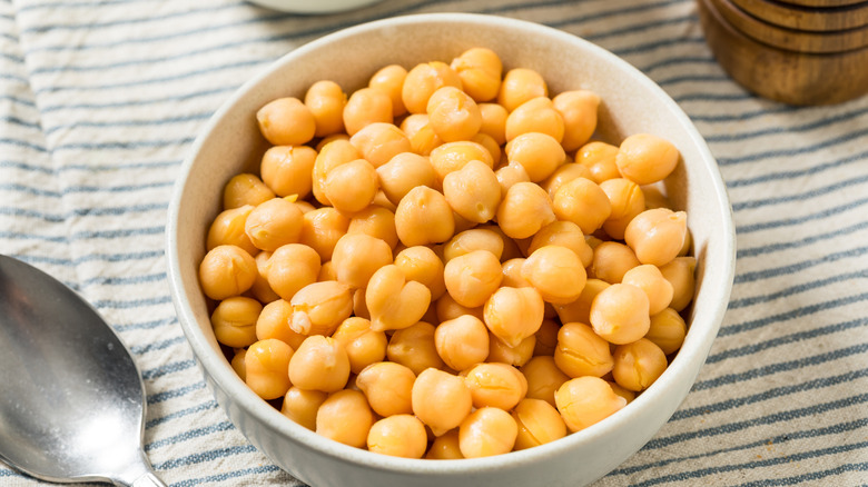 White ceramic bowl filled with canned garbanzo beans on a blue and white striped cloth placemat